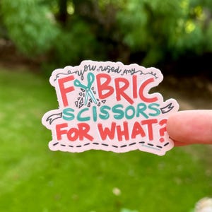 May include: A sticker with the text "You used my FABRIC SCISSORS FOR WHAT?" in red and teal lettering. The sticker features a pair of scissors and a pink border with a dashed line.