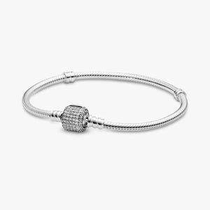 May include: A silver bracelet with a round, textured clasp encrusted with small, sparkling stones. The bracelet's band is a flexible, twisted design. The clasp is centered on the bracelet, which is displayed against a plain white background.