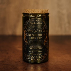 Front shot of Edinburgh Library 15 oz soy candle with a vintage green glass jar, cork top, and black and gold foil label with vintage illustrations