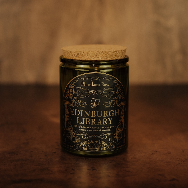 Front shot of Edinburgh Library 11 oz soy candle with a vintage green glass jar, cork top, and black and gold foil label with vintage illustrations