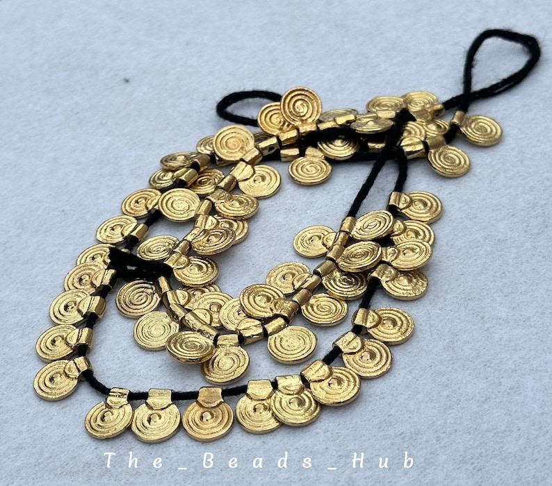 May include: A gold necklace with multiple strands of small, round, spiral-shaped beads. The beads are strung on black cord.