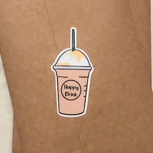 May include: A brown paper envelope with a sticker of a cartoon iced coffee drink with a straw and the text "Happy Drink" on it.