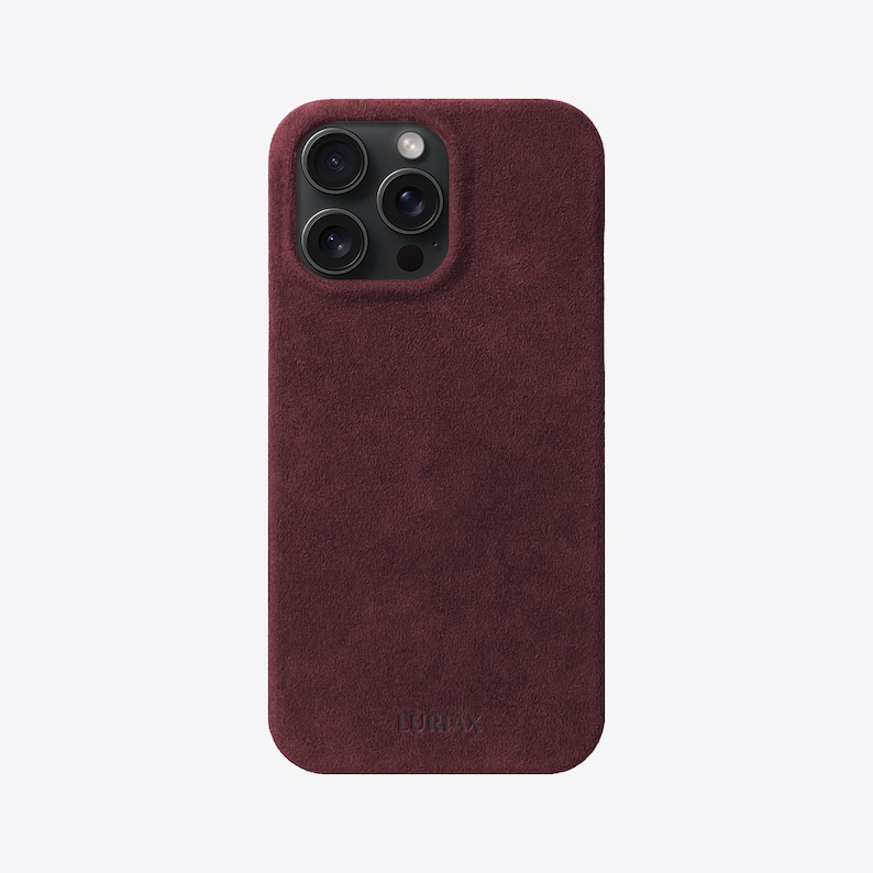 May include: A burgundy suede phone case with a raised camera bump and the word "LURVEY" embossed on the bottom.