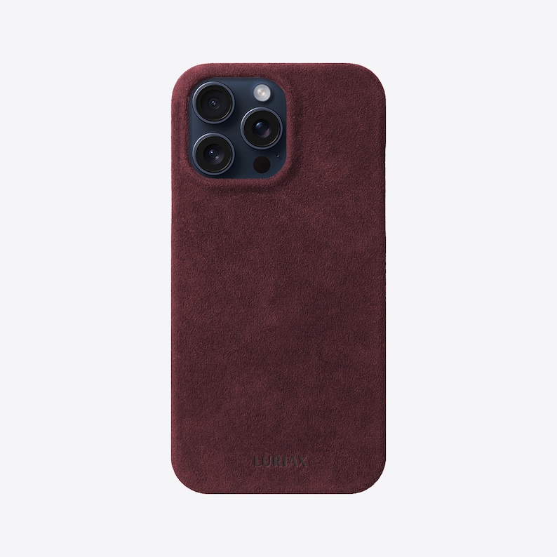 May include: A burgundy suede phone case with a raised camera bump and the word "LURVEY" embossed on the bottom.