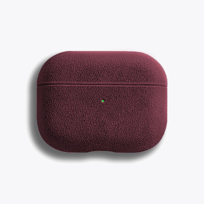 Puede incluir: Una funda de silicona de color rojo burdeos para AirPods Pro con un acabado texturizado y peludo.