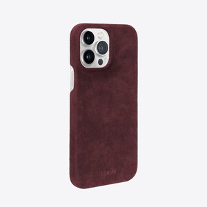 May include: A burgundy suede phone case with a silver camera lens cutout and the word "LORIIX" printed on the bottom.