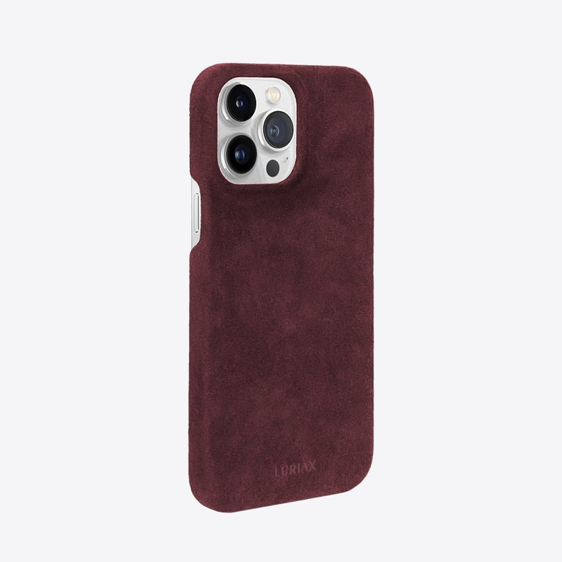 May include: A burgundy suede phone case with a silver camera lens cutout and the word "LORIIX" printed on the bottom.