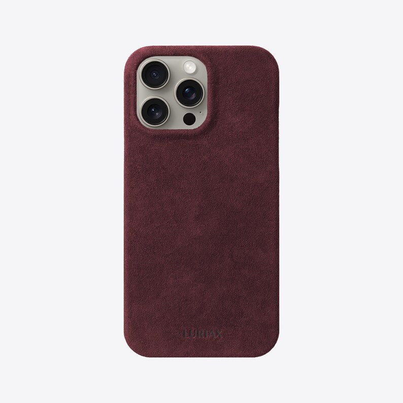 May include: A burgundy suede phone case with a raised camera bump and the word "LURVEY" embossed on the bottom.