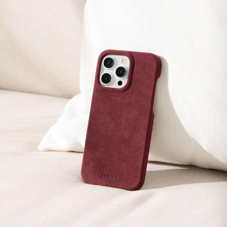 May include: A burgundy phone case with a white camera bump and the word "LUNIAX" printed on the bottom.