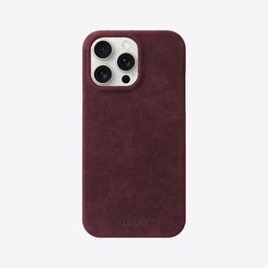 May include: A burgundy suede phone case with a white camera bump and the word "LURVEY" embossed on the bottom.