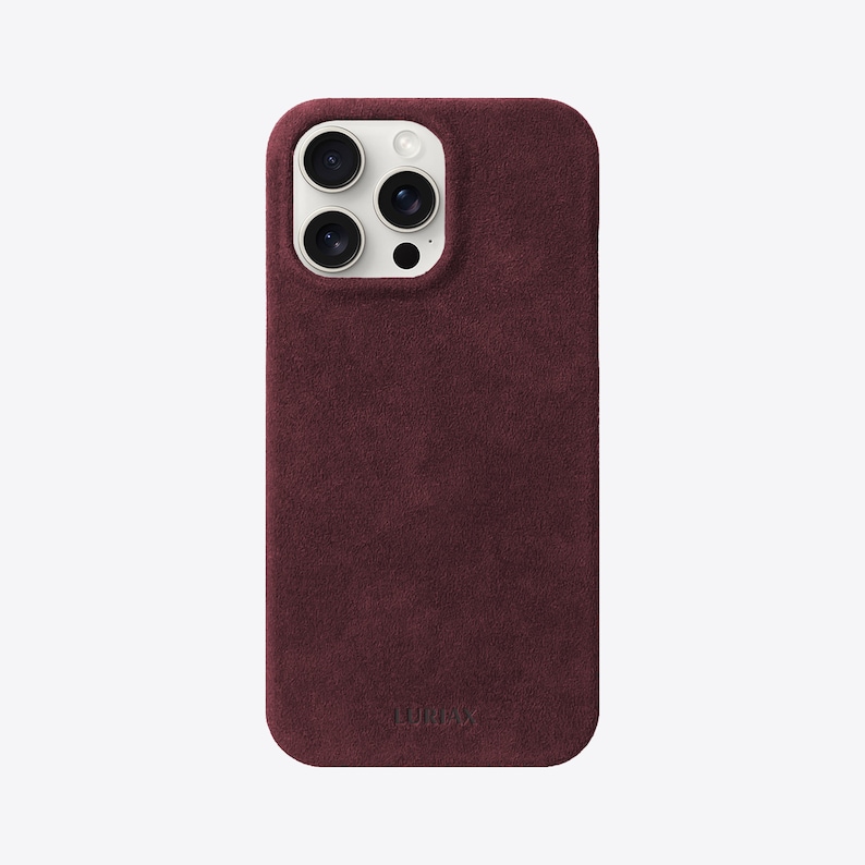 May include: A burgundy suede phone case with a white camera bump and the word "LURVEY" embossed on the bottom.