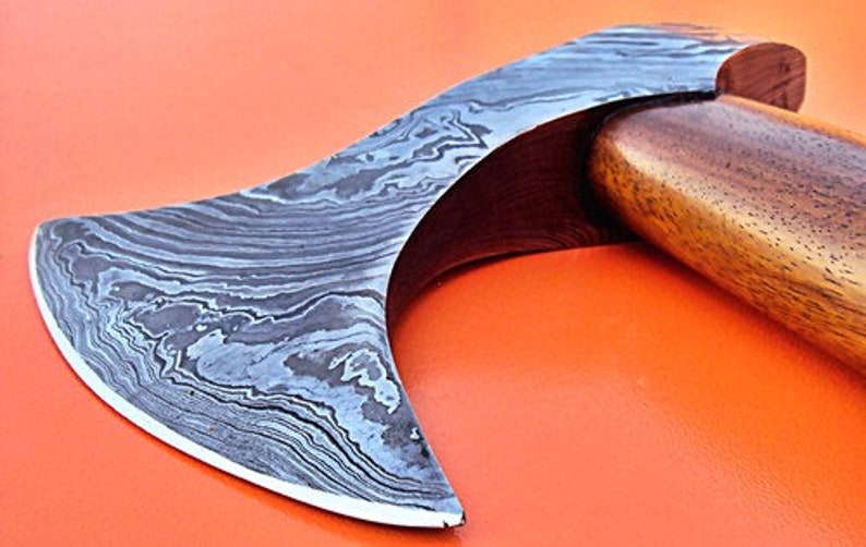 May include: A hand-forged axe with a curved blade and a wooden handle. The blade is made of Damascus steel and has a distinctive pattern.