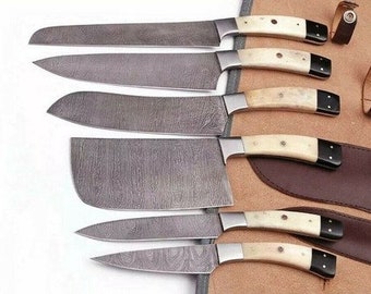 May include: Set of six kitchen knives with Damascus steel blades and bone handles. The knives are arranged in a leather roll with a brown background.