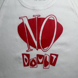 Op de afbeelding: Wit tanktop met een rode grafische afbeelding met de tekst "NO DOUBT" in een gestileerd lettertype.