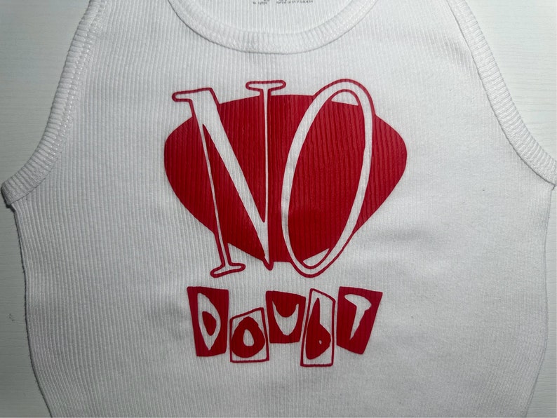 Op de afbeelding: Wit tanktop met een rode grafische afbeelding met de tekst "NO DOUBT" in een gestileerd lettertype.