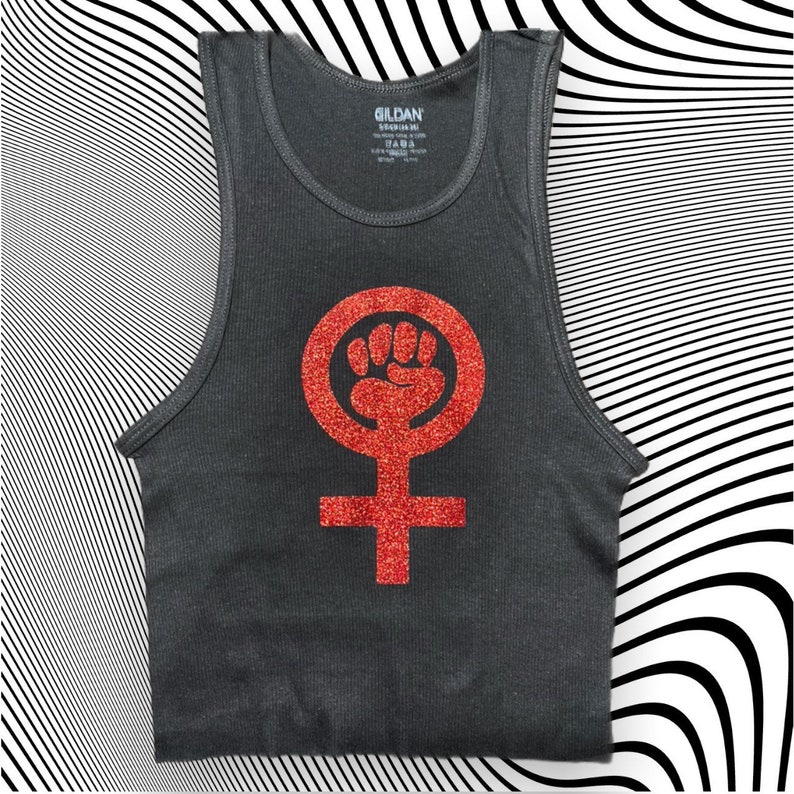 K&ouml;nnte beinhalten: Ein dunkelgraues Tanktop mit einem roten Glitzer-Feministensymbol, das eine geballte Faust in einem Kreis zeigt.