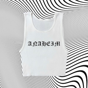 May include: White tank top with the word "ANAHEIM" printed in black gothic lettering.