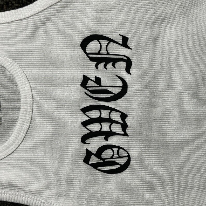 May include: White tank top with a black graphic of the word "SASS" in a stylized font.
