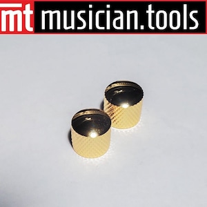 May include: Two gold-colored metal knobs with a textured surface. The knobs are round and have a raised edge.