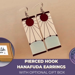 May include: A pair of pierced hook earrings featuring a white and blue design with a red sun. The earrings are inspired by the Hanafuda card game. The earrings are packaged in a brown gift box with the text "best friends - forever" on the lid.