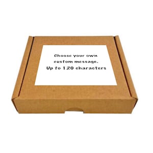 May include: A brown cardboard box with a white label that says "Choose your own custom message. Up to 120 characters."