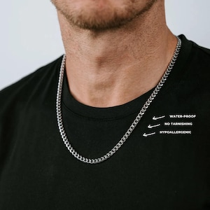 Könnte beinhalten: Eine silberfarbene Panzerkette aus Metall, die um den Hals getragen wird. Das Bild enthält Textbeschriftungen, die auf die Kette zeigen und lauten: WATER-PROOF, NO TARNISHING und HYPOALLERGENIC. Die Kette besteht aus ineinandergreifenden Gliedern.