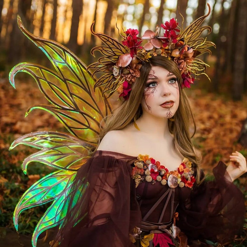 May include: A woman wearing a brown dress with a floral design and a large, elaborate headpiece made of leaves, flowers, and branches. She is also wearing iridescent butterfly wings.