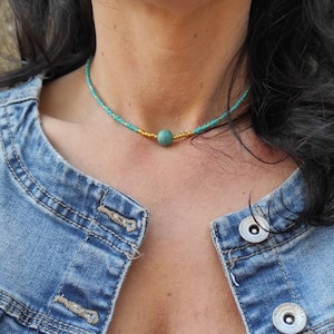 Pu&ograve; includere: Un girocollo con perline turchesi e dorate con un'unica perla turchese al centro.
