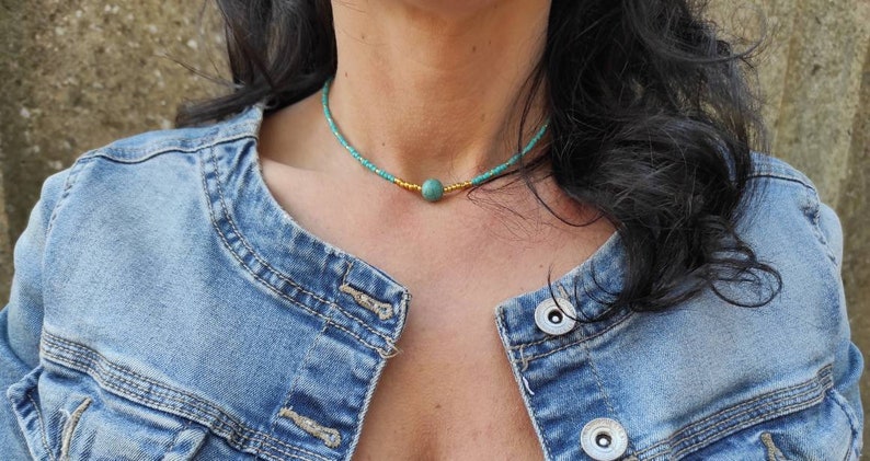 Pu&ograve; includere: Un girocollo con perline turchesi e dorate con un'unica perla turchese al centro.