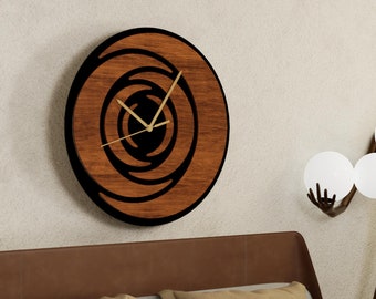 May include: A wooden wall clock with a circular design and black hands. The clock is hanging on a white wall above a bed with brown and green bedding. A bronze sculpture of a figure holding white spheres is in the background.