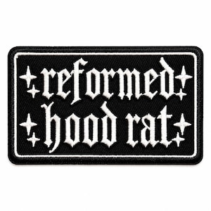 May include: A rectangular black embroidered patch with a white border. The text "reformed hood rat" is stitched in white using a gothic-style font. Four small white four-pointed star icons are positioned on the left and right sides of the text.