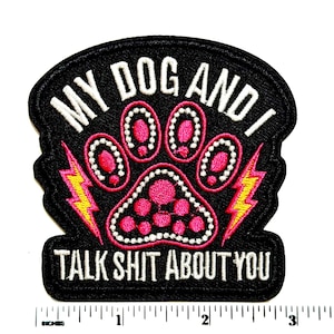 May include: A black embroidered patch featuring a pink paw print outlined in white, flanked by two yellow lightning bolts. The text reads MY DOG AND I TALK SHIT ABOUT YOU in white. A ruler shows the patch is approximately 3.5 inches wide.