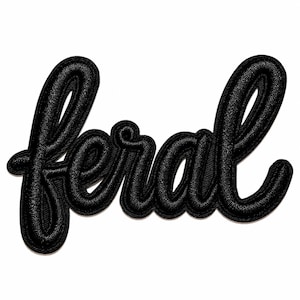 May include: A black embroidered patch featuring the word feral in a cursive, script-style font. The lettering has a raised, textured appearance with a thick, stitched border that follows the contours of the letters against a plain background.