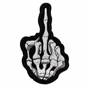 May include: An embroidered patch featuring a white skeletal hand making a middle finger gesture. The bones are detailed with grey shading and outlined in thick black thread, creating a high-contrast design on a solid black background.