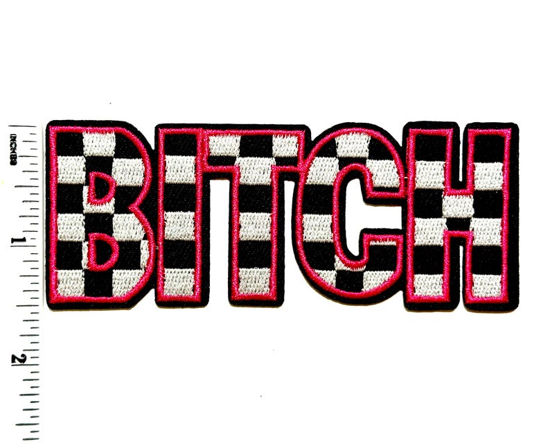 Pu&ograve; includere: Toppa ricamata con la parola "BITCH" in grassetto, a blocchi. Le lettere sono nere con un motivo a scacchi bianchi e neri, bordate di rosa acceso. La toppa &egrave; larga circa 7,6 cm.