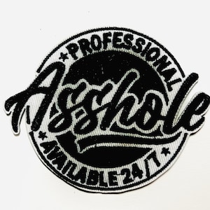 May include: A black and white embroidered patch with the words "PROFESSIONAL Asshole AVAILABLE 24/7" in a circular design. The patch is approximately 3 inches in diameter.