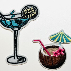 May include: Embroidered patches featuring a margarita cocktail with a lime slice and a coconut drink with a straw and umbrella. The patches have a white border and are in shades of blue, brown, pink, yellow, and black.