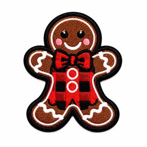 May include: A gingerbread person embroidered patch featuring a brown body with white icing details, pink cheeks, and black eyes. The figure wears a red and black buffalo plaid shirt with a matching red bow tie and two white circular buttons.