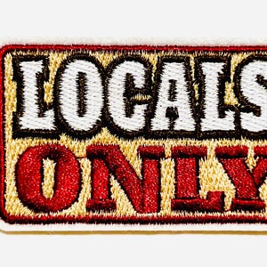 May include: Embroidered patch with the words "LOCALS ONLY" in white and red lettering. The patch has a tan background with a red border and measures approximately 2 inches by 1 inch.