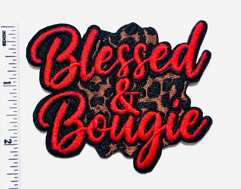 May include: Embroidered patch with the words "Blessed & Bougie" in red script. The text is outlined in black and sits atop a leopard print background. The patch measures approximately 2 inches in height.