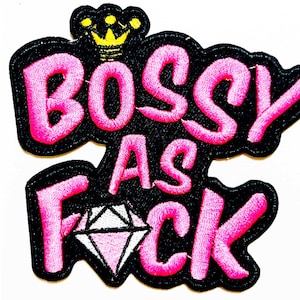 May include: Embroidered patch with the words "Bossy As Fck" in pink, outlined in black. A yellow crown sits above the word "Bossy", and a diamond graphic is below. The patch is approximately 3 inches in length.