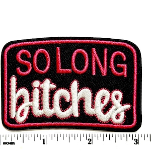 May include: A rectangular embroidered patch with a black background and a pink border. The text SO LONG is stitched in pink capital letters above the word bitches in white cursive script. A ruler shows the patch is approximately 3.5 inches wide.