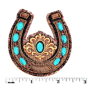 May include: Embroidered horseshoe patch with a brown glitter outline and turquoise accents. The horseshoe features a central turquoise oval surrounded by gold filigree. Turquoise oval accents are evenly spaced along the horseshoe's arms.