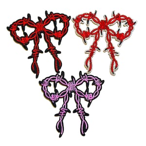 May include: Three embroidered patches in the shape of a bow, with a barbed wire design. The patches are in red, pink, and red with silver trim. The patches are on a white background.