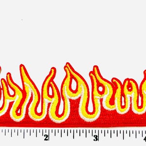 May include: Embroidered flame patch with red, yellow, and white colors. The patch is approximately 5 inches long. The flames have a detailed design, suitable for jackets, bags, or other apparel.