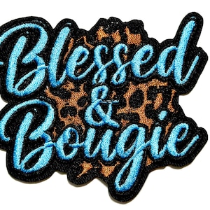 May include: Embroidered patch with the words "Blessed & Bougie" in light blue script. The text is outlined in black and set against a leopard print background. The patch has a black border.