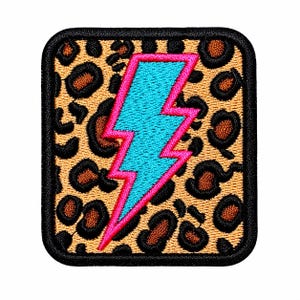 May include: A square embroidered patch with rounded corners featuring a bright blue lightning bolt outlined in hot pink. The background of the patch displays a tan and brown leopard print pattern, and the entire edge is finished with a black border.