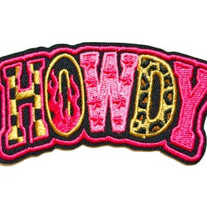 May include: Embroidered patch with the word "HOWDY" in a bold, stylized font. The letters are in pink, gold, and black, with flame and leopard print details. The patch is outlined in black and pink, and measures approximately 3 inches wide.