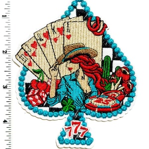 May include: Embroidered patch in the shape of a spade, featuring a cowgirl with red hair, playing cards, and casino elements. The design includes playing cards, cherries, a cactus, and a lucky 777 symbol. The patch is outlined in turquoise.
