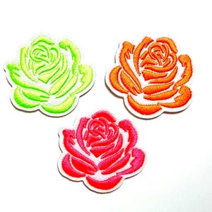 May include: Three embroidered rose patches in vibrant colors: lime green, orange, and red. Each patch features a detailed floral design with a white border, perfect for adding a decorative touch to clothing or accessories.